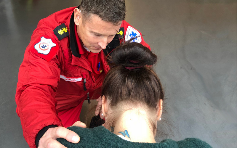 En ambulansearbeider snakker beroligende og trøstende til en ung kvinne.