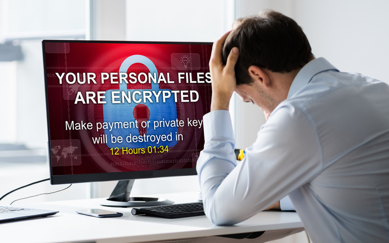 Oppgitt mann foran PC-skjerm med meldingen: Your personal files are encryted....
