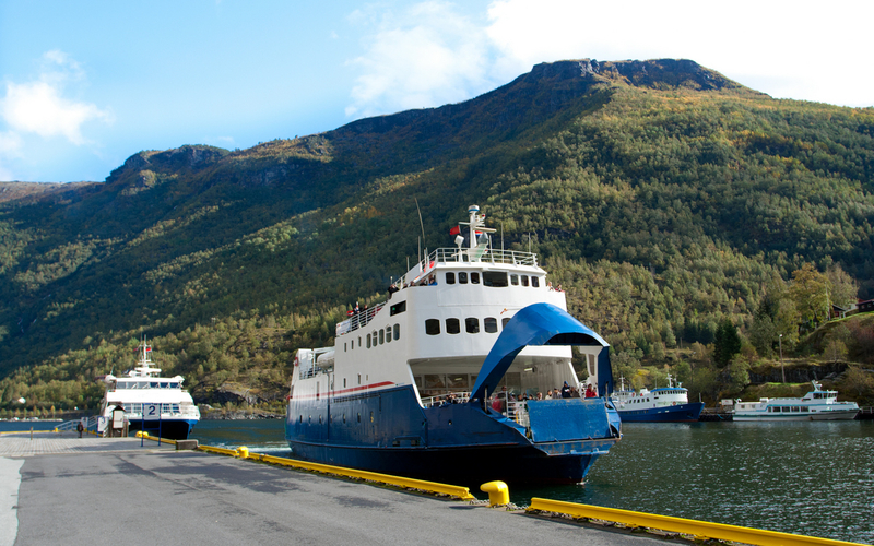 En bilferge og noen andre mindre passasjerbåter ligger til kai et sted langs norskekysten.