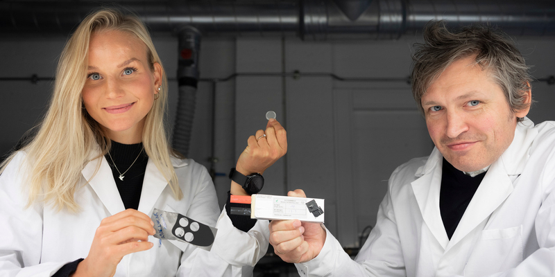 Mann og kvinne i lab-frakk holder opp eksempler på litium-batterier