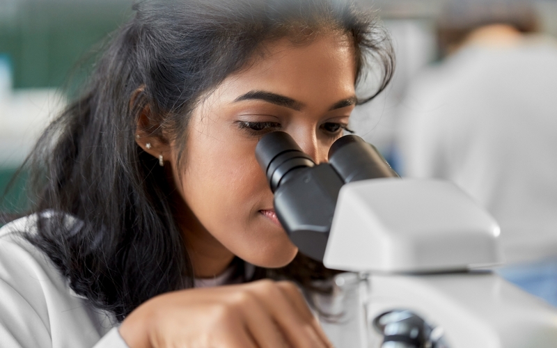 Kvinner kikker i mikroskop