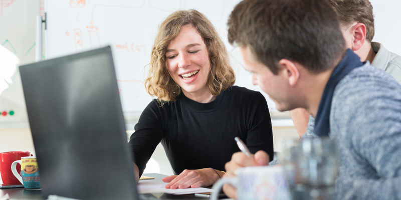 Woman and to men gathered round a computer
